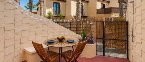 A patio with a round table, chairs, and a fruit bowl.
