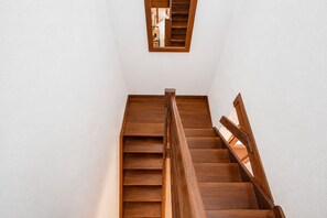 Eine Holztreppe mit Geländer und einem kleinen Fenster am Obergeschoss.