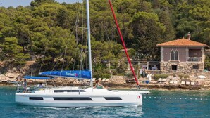 A sailboat with a blue cover and a stone building with a red roof in the background. - Sun-Kissed Sailing Adventure in the Ionian Islands, Lefkada (Lefkada)