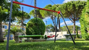 Un jardín con un columpio, una banca y una pequeña mesa.
