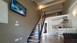 Una escalera que conduce a un dormitorio en entrepiso con una zona de cocina abajo.