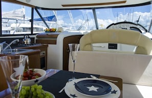 A yacht interior with a dining area, a kitchen, and a view of the marina. - Sun-Kissed Sailing Adventure in Northern Croatia (Novalja)