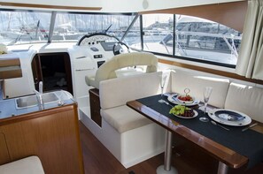 A yacht interior with a dining area, a steering wheel, and a view of the marina. - Sun-Kissed Sailing Adventure in Northern Croatia (Novalja)