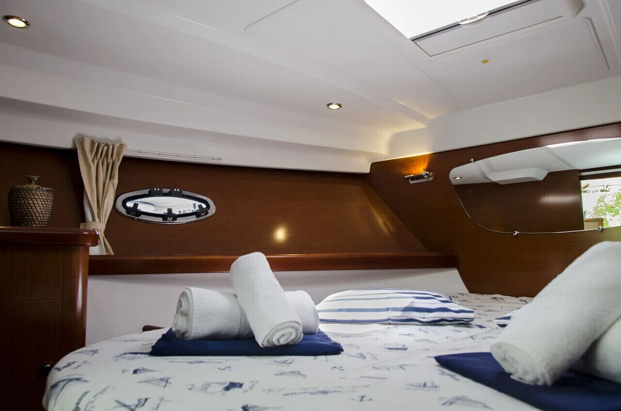 A modern interior with a bed, rolled towels, a circular window, and a wooden accent wall.