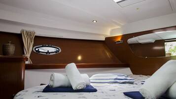 A modern interior with a bed, rolled towels, a circular window, and a wooden accent wall.