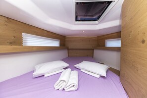 A small, single-bed room with a wooden headboard, a window with blinds, and a purple bedspread. - Sun-Kissed Sailing Adventure in Zadar, Croatia (Zadar)
