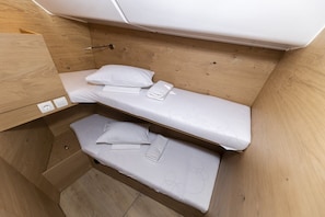 Een kleine kamer met twee stapelbedden, houten wanden en een klein bureau.