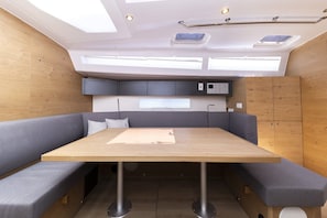 A compact, modern interior with a wooden table, grey cushioned seating, and built-in cabinets. - Sun-Kissed Sailing Adventure in Zadar, Croatia (Zadar)