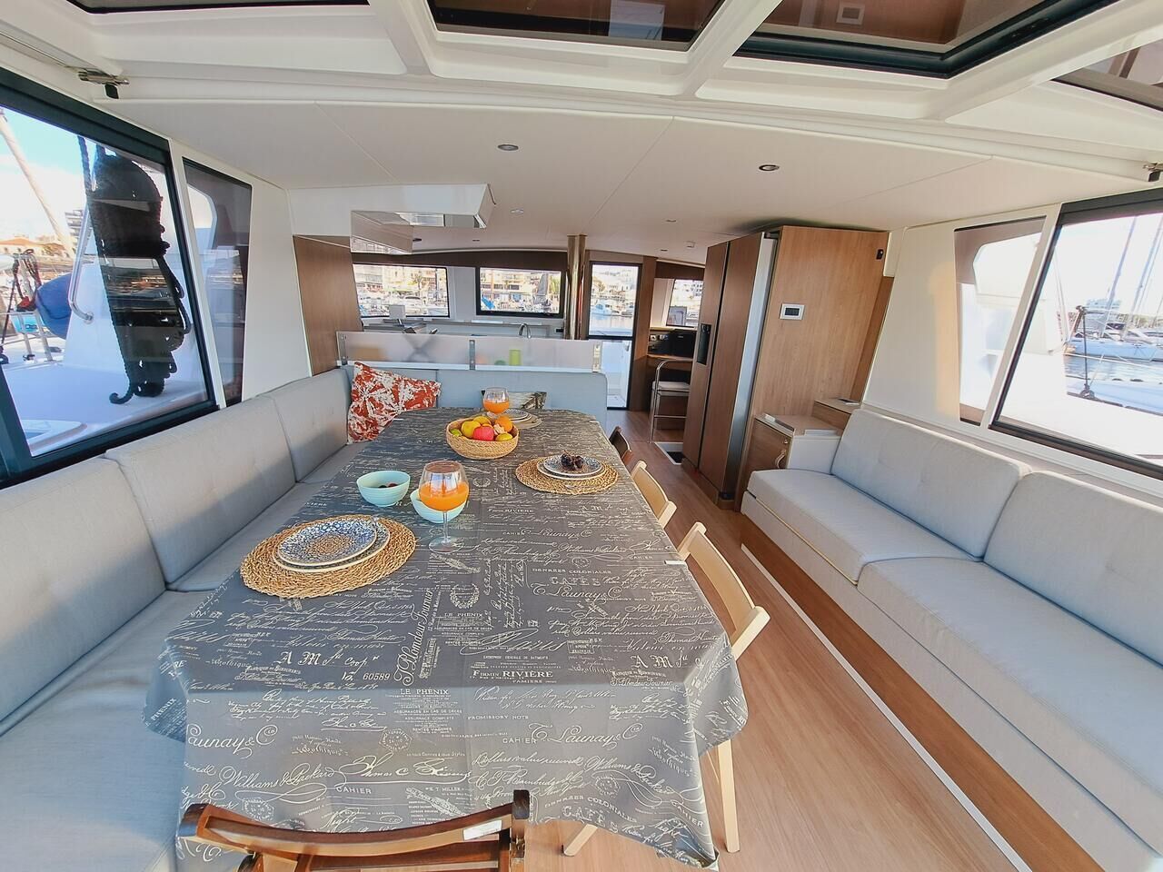 Een eetgedeelte met een tafel voor vier personen, een bank en uitzicht op de jachthaven.