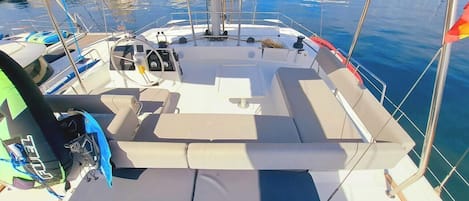 Un pont de bateau équipé de sièges, d’un volant et offrant une vue sur une marina où se trouvent d’autres bateaux.