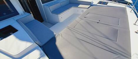 A boat deck with seating areas, a control panel, and a view of other boats in the marina.