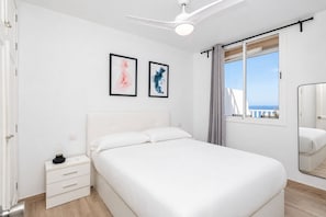 Ein Schlafzimmer mit Bett, Nachttisch und einem Fenster mit Blick.