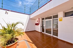 A building with a glass door entrance, a red fire alarm, and a potted plant. - GuestReady - Balcon de Amadores Sea View (Puerto Rico)