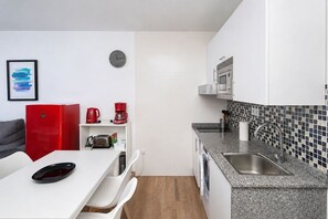 A compact kitchen with a microwave, coffee maker, and toaster on the counter. - GuestReady - Balcon de Amadores Sea View (Puerto Rico)