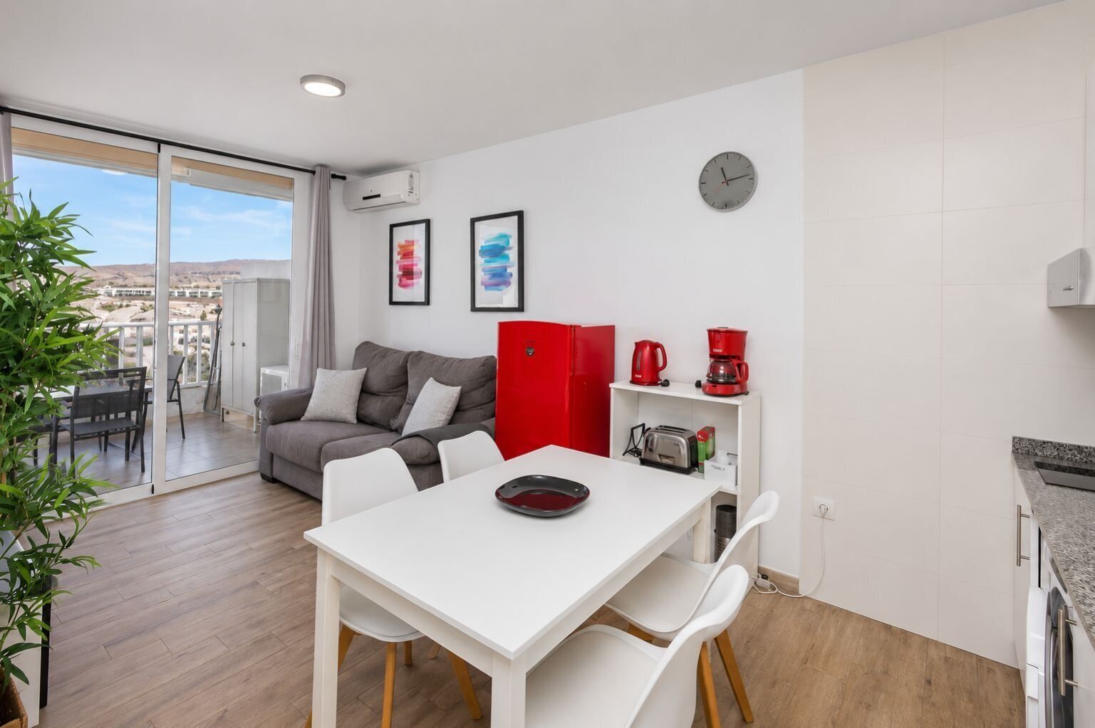 Ein modernes Apartment mit Essbereich, einer Couch, einem roten Schrank und einer Küchenzeile.
