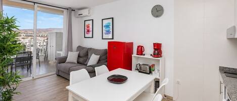 Ein modernes Apartment mit Essbereich, einer Couch, einem roten Schrank und einer Küchenzeile.