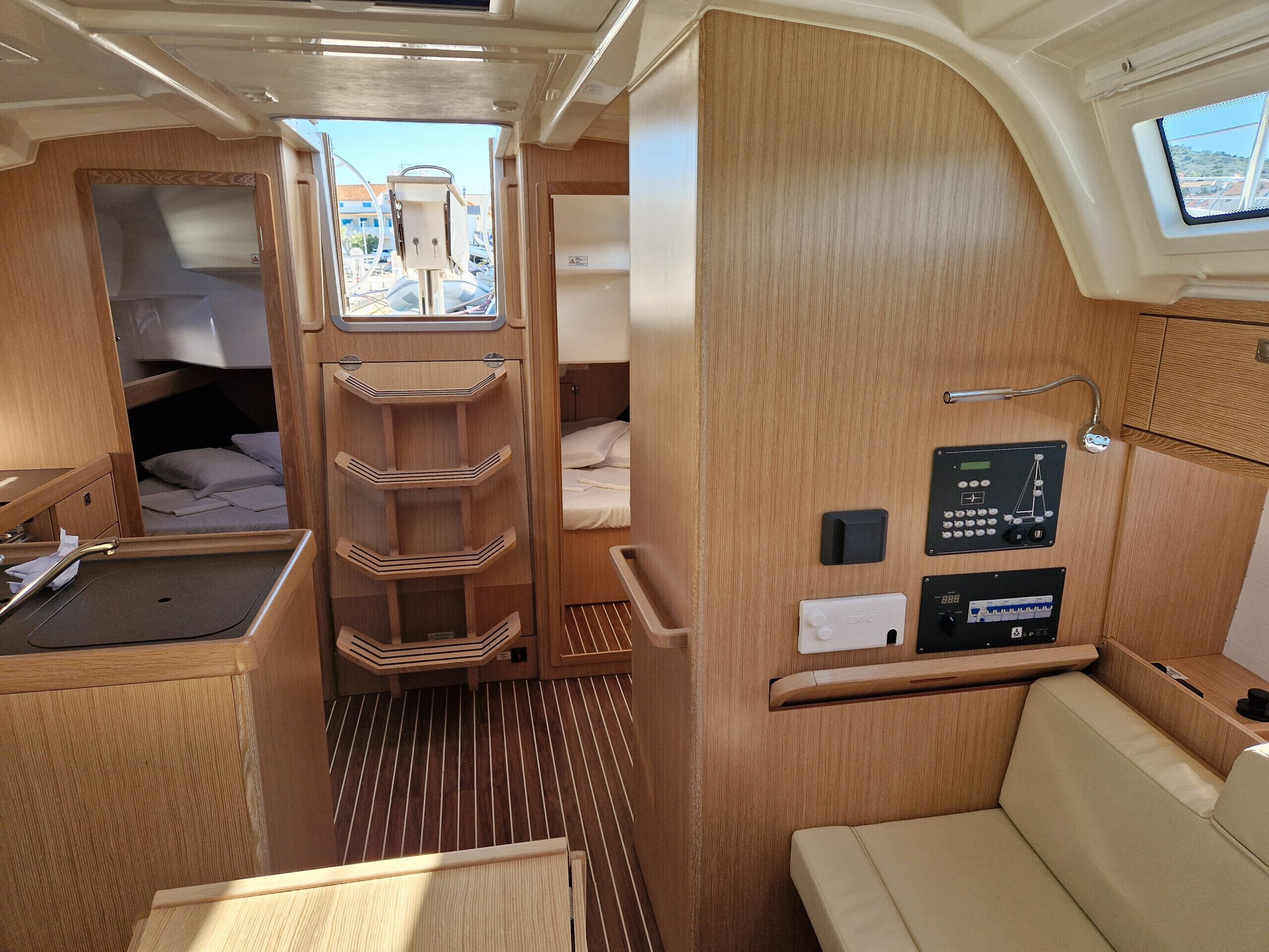 A compact interior with a bunk bed, a small kitchenette, a control panel, and a window offering a view of the outside.