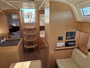 Een compact interieur met een stapelbed, een klein keukentje, een bedieningspaneel en een raam met uitzicht.
