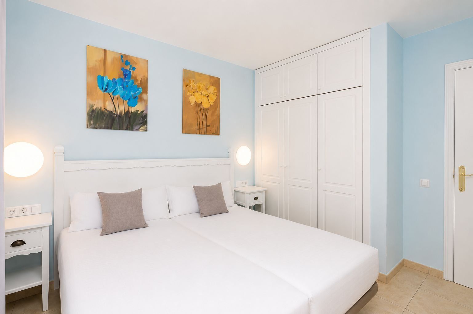 Une chambre à coucher comprenant un lit, des tables de chevet, des œuvres d’art murales et une armoire.