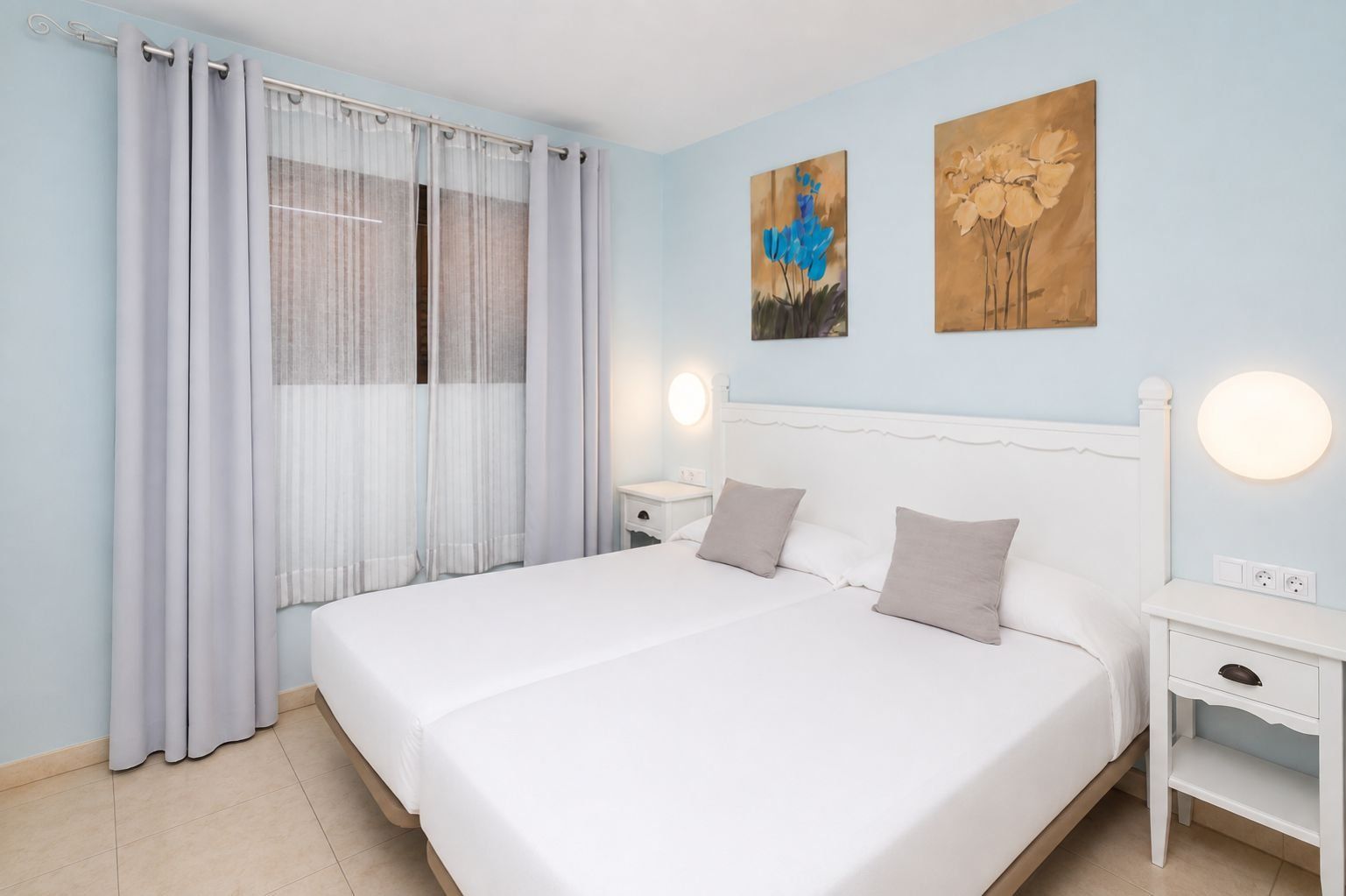 Una camera da letto con un letto grande, due comodini, un tavolino e una finestra con tende leggere.