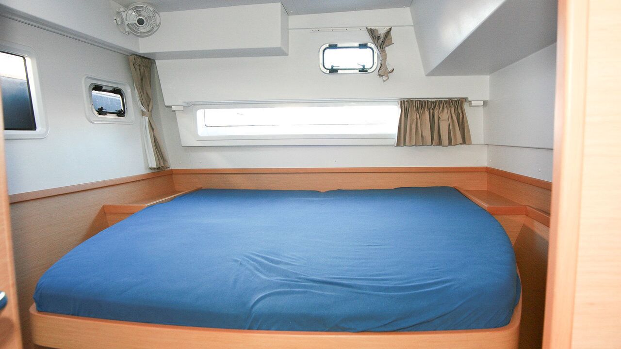 Habitación pequeña con una cama individual, una ventana con cortinas, un ventilador y otra ventana con vistas.