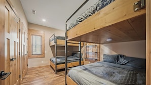 A bunk bed room with wooden floors, a window, and a door. - Sunset Point on Winter Lake (Winter)