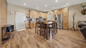 A modern kitchen with wooden cabinets, a stainless steel refrigerator, and a dining table with chairs. - Sunset Point on Winter Lake (Winter)