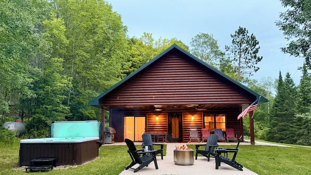 A log cabin with a porch, outdoor seating, and a fire pit. - Sunset Point on Winter Lake (Winter)