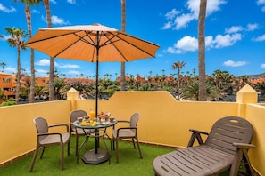 An outdoor seating area with a table, chairs, and a large umbrella. - GuestReady - Modern Stay with Pool and Terrace (Corralejo)