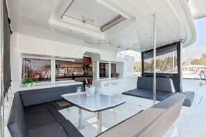 A yacht interior with a dining area, seating, and a view of the marina. - Sun-Kissed Sailing Adventure in Islas Sarónicas (Alimos)