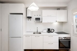 A modern kitchen with white cabinetry, a built-in microwave, a coffee maker, and an oven. - GuestReady - Bergantín Bañaderos Sea View (Arucas)
