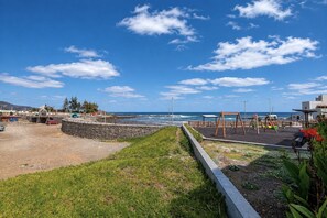 A coastal view with a playground, a parking area, and a clear sky. - GuestReady - Bergantín Bañaderos Sea View (Arucas)