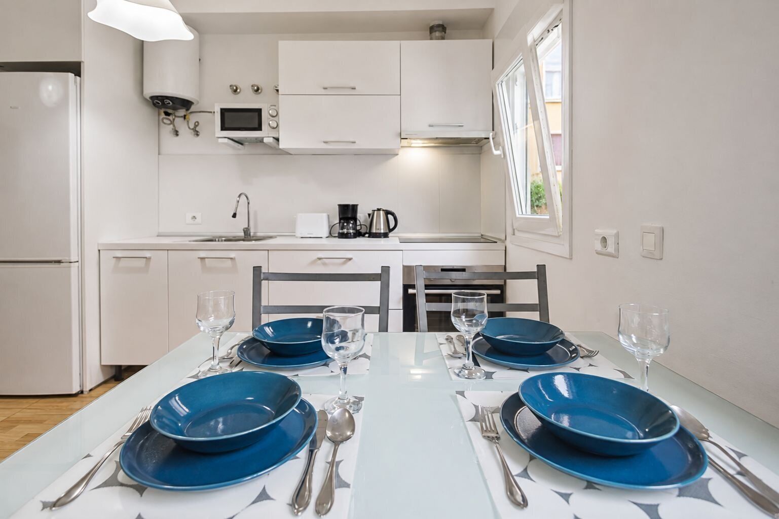 Una cocina moderna con gabinetes blancos, microondas y cafetera.