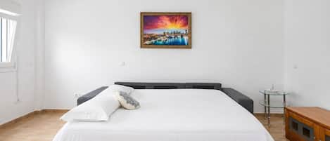 Un dormitorio con una cama grande, una mesita de noche pequeña y un cuadro en la pared.