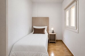 A small, narrow room with a single bed, a nightstand with a lamp, and a window. - GuestReady - Bergantín Bañaderos Sea View (Arucas)