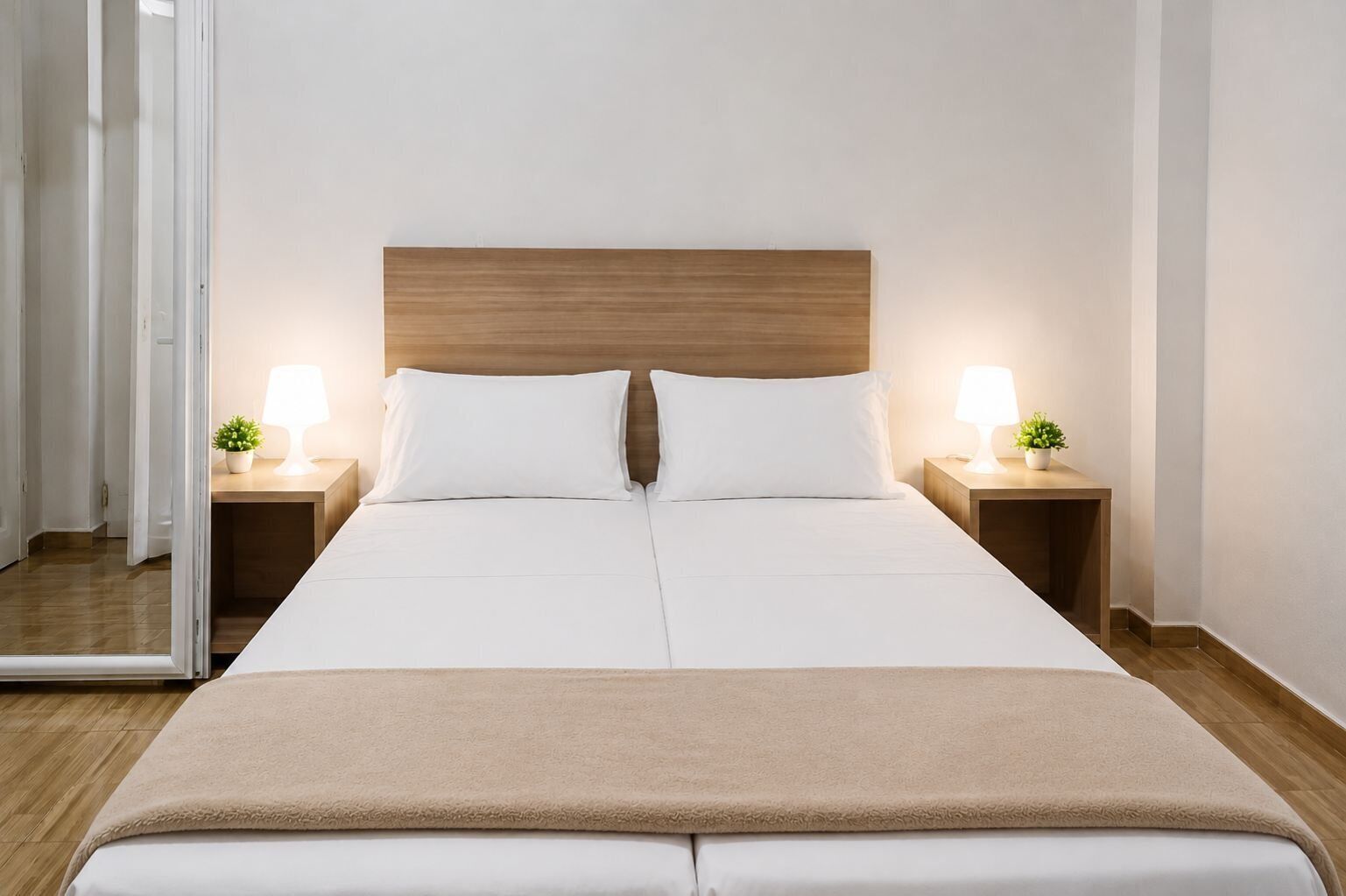 A hotel room with a large bed, two bedside tables with lamps, and a wooden headboard.