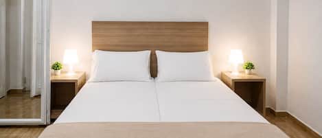 A hotel room with a large bed, two bedside tables with lamps, and a wooden headboard.