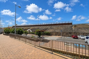 A paved walkway with a metal fence, a covered seating area, and a stone wall in the background. - GuestReady - Bergantín Bañaderos Sea View (Arucas)