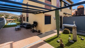 Een moderne buitenpatio met een zwembad, zitgedeelte en een barbecue.