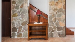 Een houten bank met een lamp tegen een stenen muur, een houten deur en een trap.