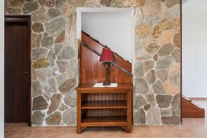 Eine hölzerne Bank mit einer Lampe an einer Steinwand, eine Holztür und eine Treppe.