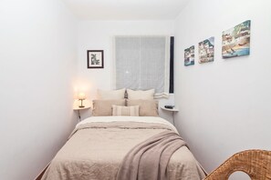 A bedroom with a bed, a bedside table with a lamp, a window with curtains, and three wall-mounted paintings. - GuestReady - Villa Datana with Pool (Mogán)