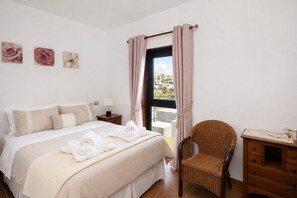 A hotel room with a bed, a chair, a nightstand, and a view of the outdoors. - GuestReady - Villa Datana with Pool (Mogán)