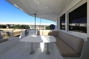 Cubierta de barco con mesa, asientos y vista de un edificio.