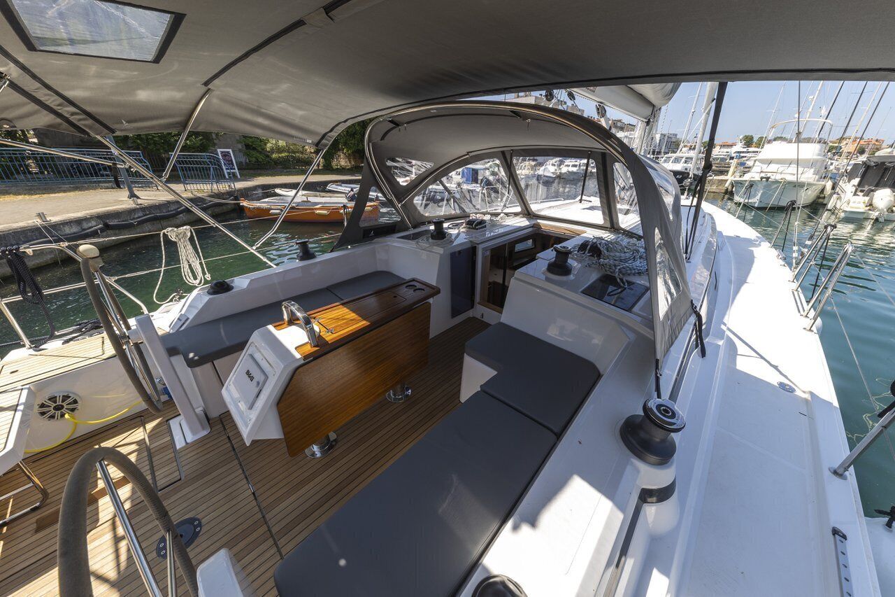 A boat's deck with a wooden floor, a cushioned seating area, and a steering wheel.