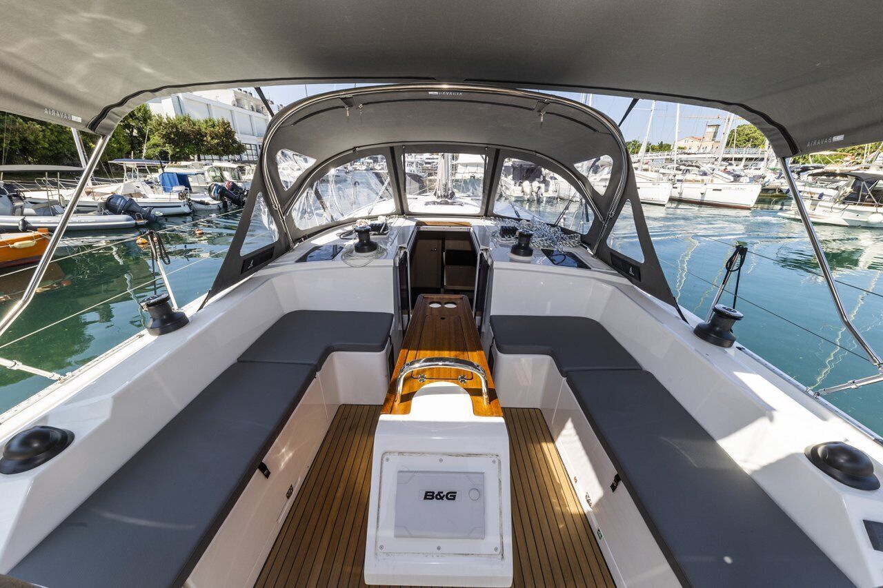 A boat deck with a central seating area, a B&G logo, and a view of the marina.