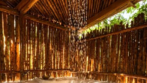 Una habitación con techo de bambú, una fuente colgante y piso reflectante.