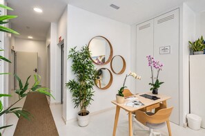 Un espace de bureau moderne comprenant un bureau, des chaises, une plante en pot, un miroir et une porte.