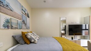 A modern bedroom with a bed, a TV, and artwork on the wall. - GuestReady - 01D Livian Suites Ext 2pax (Las Palmas de Gran Canaria)