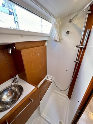 A compact bathroom with a shower, a sink, and a window. - Sun-Kissed Sailing Adventure in Zadar, Croatia (Bibinje)